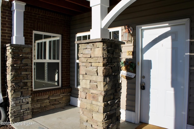 doorway to property with stone siding and brick siding