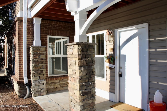 view of exterior entry with brick siding and stone siding