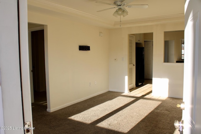 unfurnished room with carpet flooring, a raised ceiling, crown molding, and baseboards