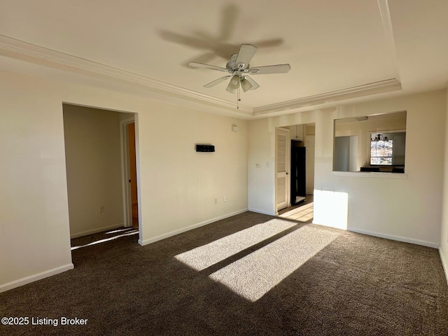 empty room featuring ornamental molding, a tray ceiling, carpet floors, baseboards, and ceiling fan