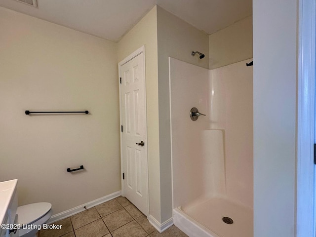 bathroom featuring tile patterned flooring, toilet, baseboards, and walk in shower