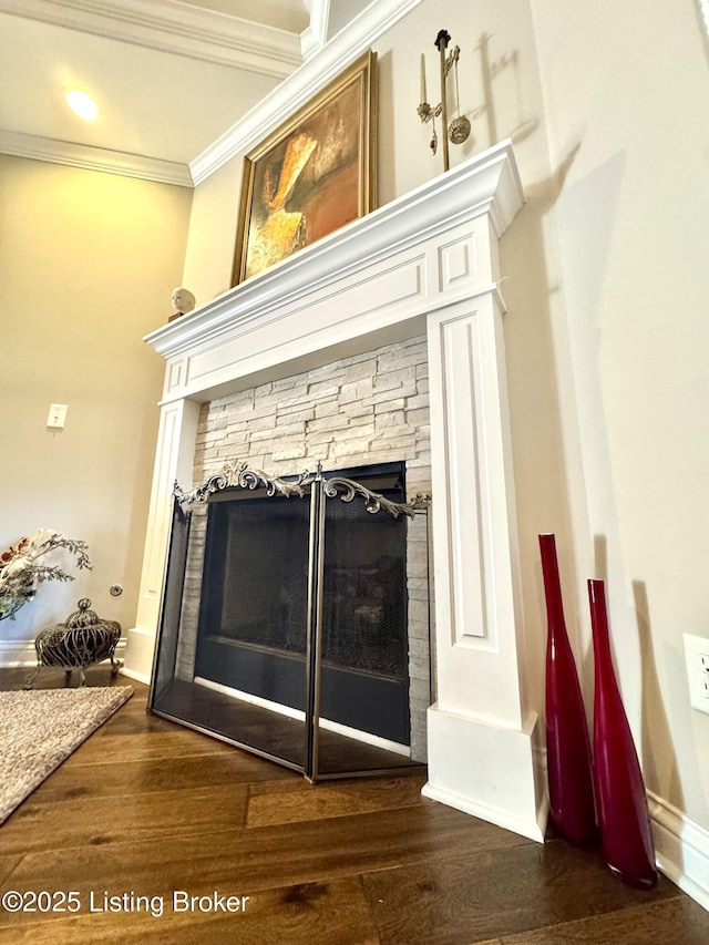 interior details featuring ornamental molding, a fireplace, baseboards, and wood finished floors