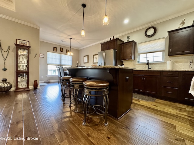 kitchen with a breakfast bar area, a healthy amount of sunlight, stainless steel refrigerator with ice dispenser, and dark wood-style flooring