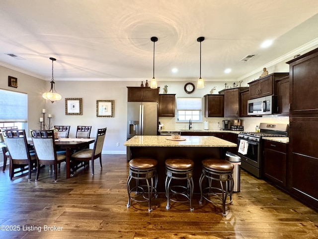 kitchen featuring dark wood-style floors, a sink, stainless steel appliances, dark brown cabinetry, and a center island