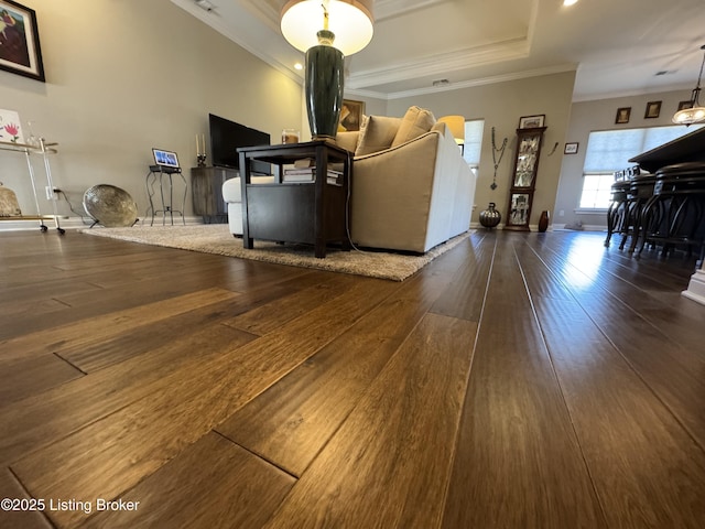 unfurnished living room with ornamental molding, baseboards, a tray ceiling, and hardwood / wood-style floors