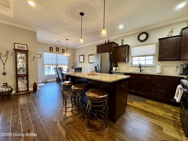 kitchen with a sink, backsplash, a kitchen island, dark wood-style floors, and appliances with stainless steel finishes