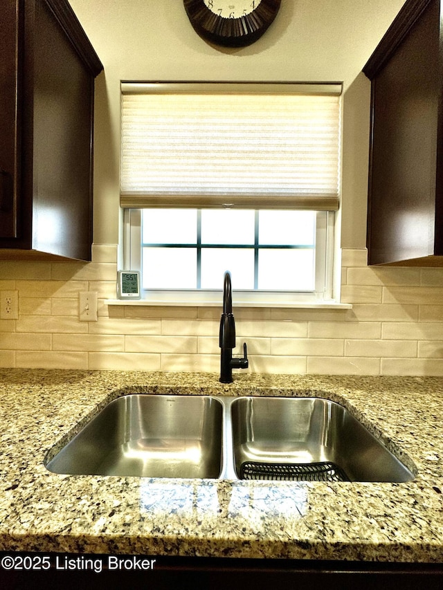 room details featuring a sink, tasteful backsplash, and dark brown cabinets