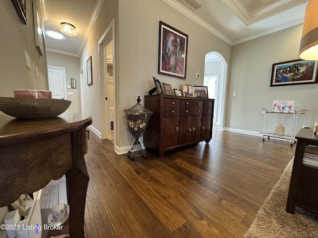 hall featuring visible vents, baseboards, ornamental molding, dark wood-style floors, and arched walkways