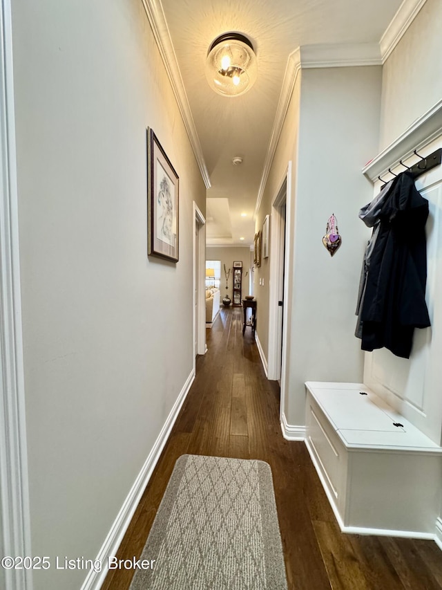 hallway with dark wood-style floors, baseboards, and ornamental molding