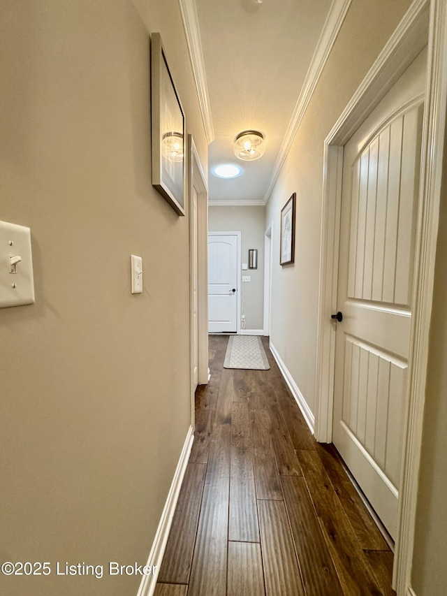 hall with dark wood-style floors, crown molding, and baseboards