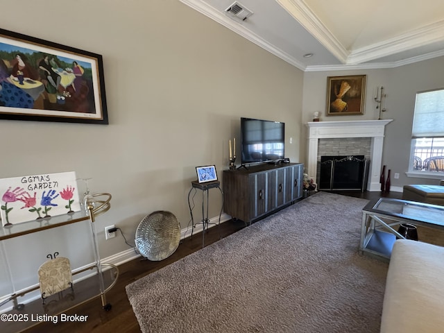 living area with visible vents, crown molding, baseboards, a fireplace with flush hearth, and wood finished floors