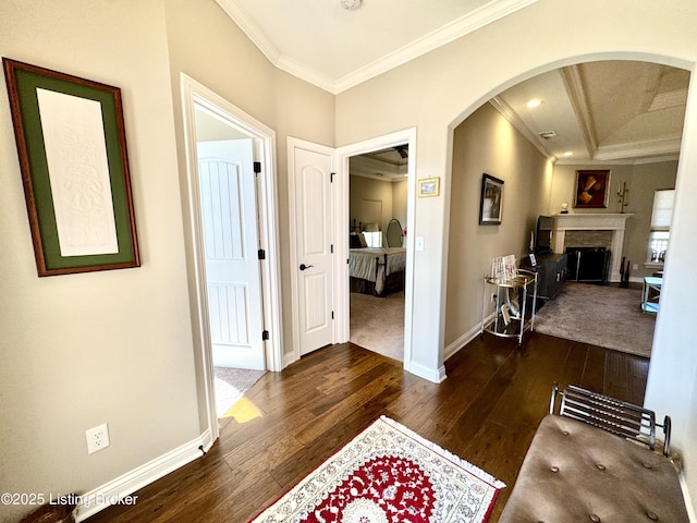 entryway featuring arched walkways, a fireplace, dark wood finished floors, and crown molding