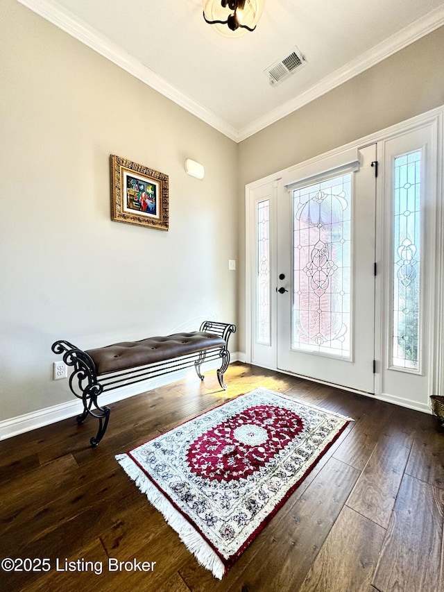 foyer entrance with visible vents, hardwood / wood-style floors, baseboards, and ornamental molding