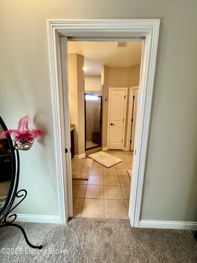 corridor with light tile patterned floors, baseboards, visible vents, and light carpet