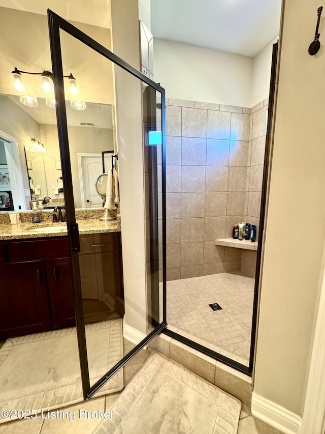 full bath featuring tile patterned floors, a stall shower, vanity, and baseboards