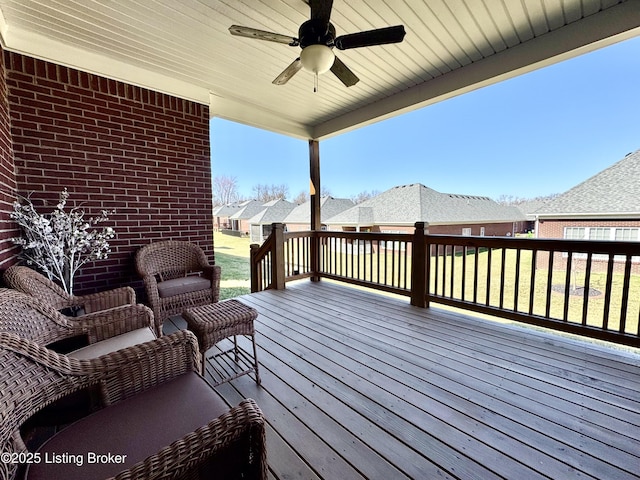 wooden deck featuring a yard, a residential view, and a ceiling fan