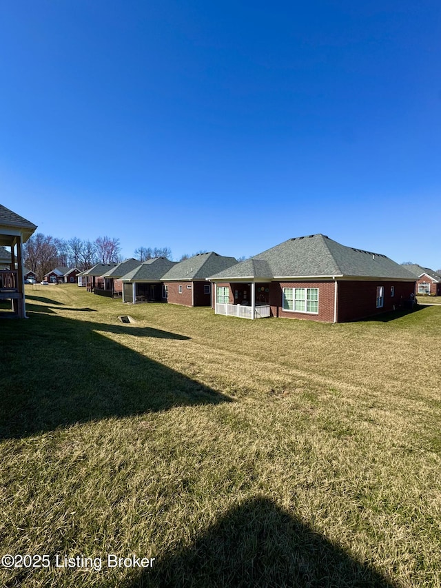 rear view of property featuring brick siding and a lawn