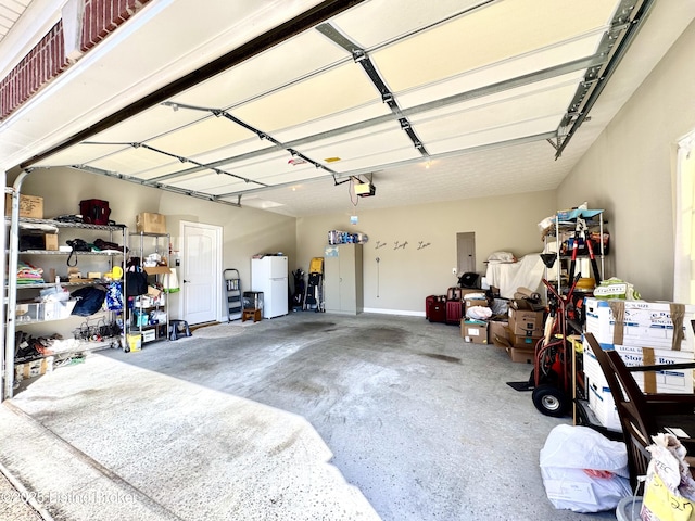 garage featuring electric panel, a garage door opener, and freestanding refrigerator