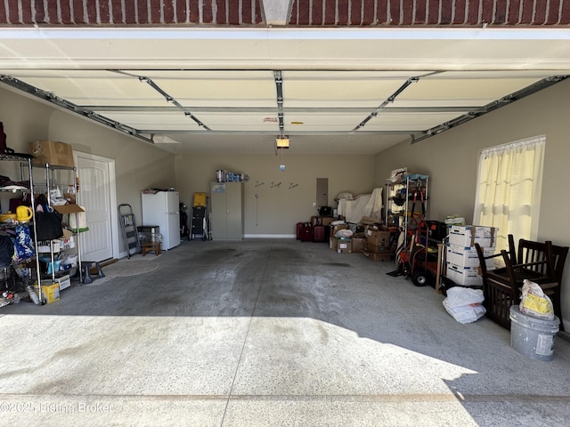 garage featuring electric panel, a garage door opener, and freestanding refrigerator