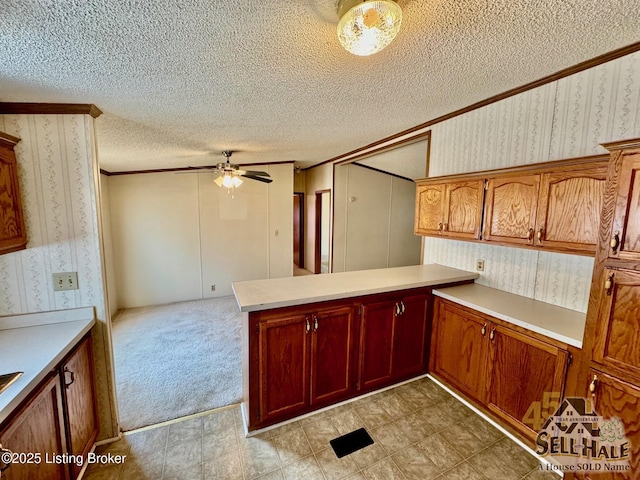 kitchen with a textured ceiling, light colored carpet, a peninsula, and wallpapered walls