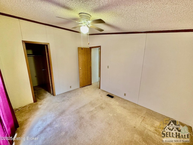 unfurnished bedroom with visible vents, a textured ceiling, ornamental molding, and carpet