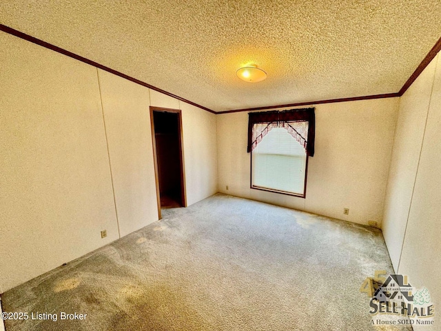 unfurnished bedroom with a textured ceiling, vaulted ceiling, carpet flooring, and ornamental molding