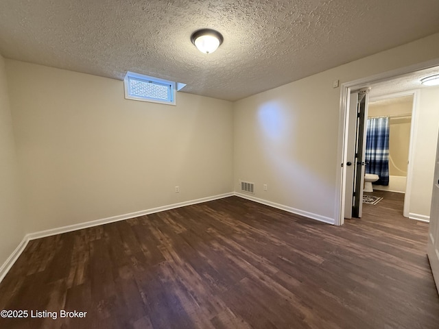 spare room featuring dark wood-style floors, visible vents, and baseboards