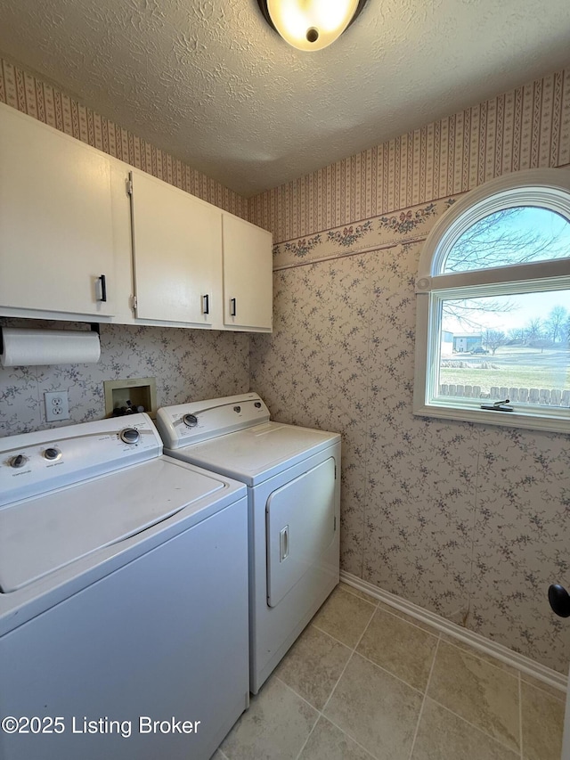 washroom with cabinet space, a textured ceiling, washing machine and dryer, and wallpapered walls