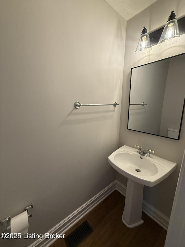 bathroom featuring wood finished floors, baseboards, and visible vents