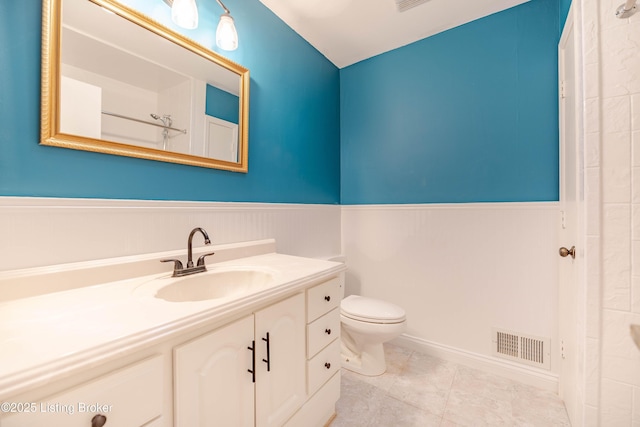 bathroom featuring visible vents, vanity, toilet, and wainscoting