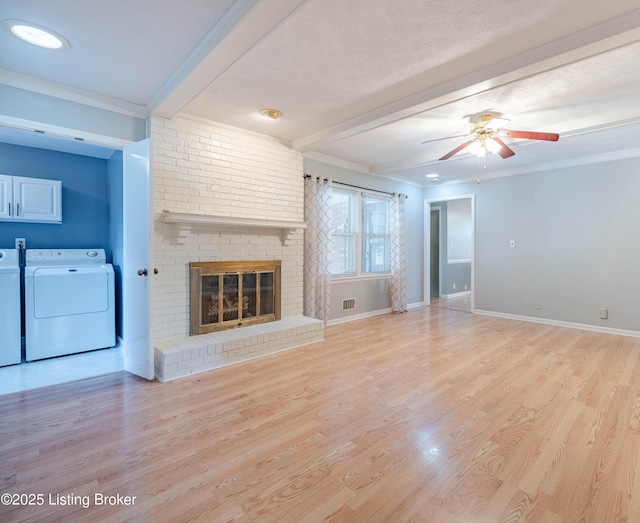 unfurnished living room featuring washer and dryer, beam ceiling, and light wood-style flooring