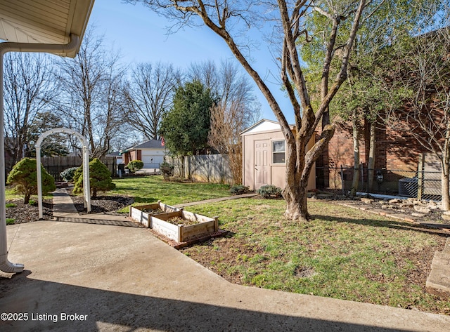 view of yard with a garden, a fenced backyard, an outdoor structure, and a shed