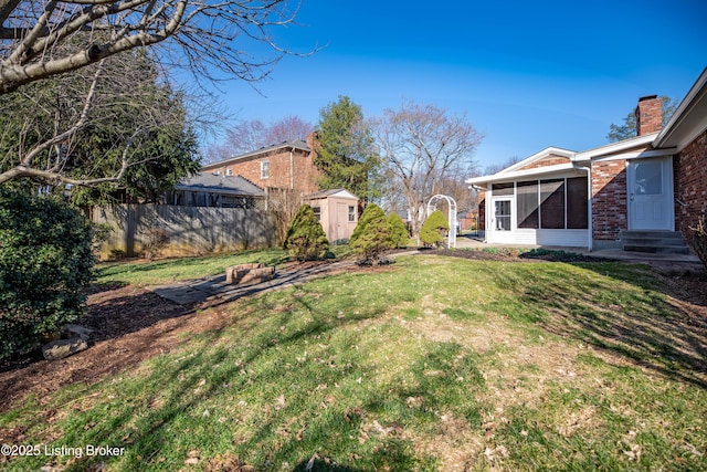 view of yard featuring an outbuilding, fence, a sunroom, entry steps, and a storage shed