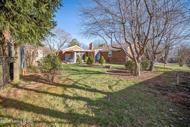 view of front of house featuring a front lawn, fence, brick siding, and a chimney