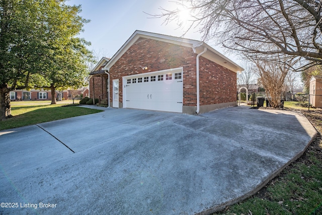 view of home's exterior featuring brick siding, fence, concrete driveway, a lawn, and an attached garage