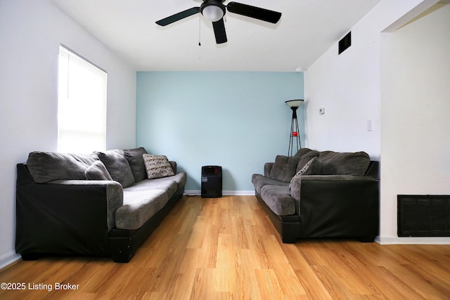 living room with light wood finished floors, visible vents, ceiling fan, and baseboards