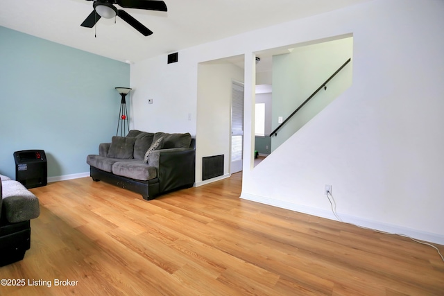 living area featuring a ceiling fan, visible vents, baseboards, stairs, and light wood-style floors