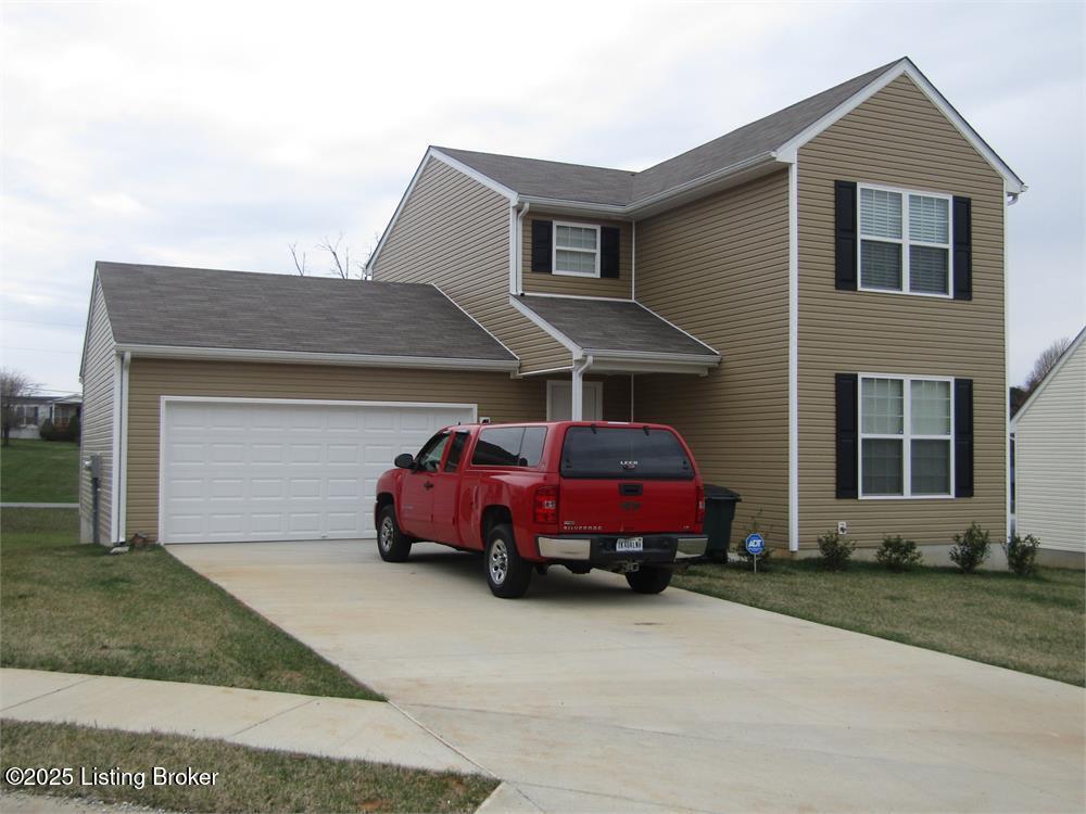 traditional-style house with a front lawn, an attached garage, and driveway