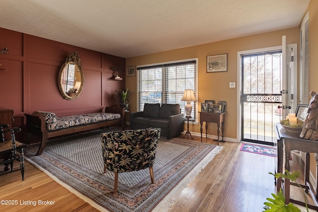 living area with light wood-type flooring, baseboards, and a textured ceiling