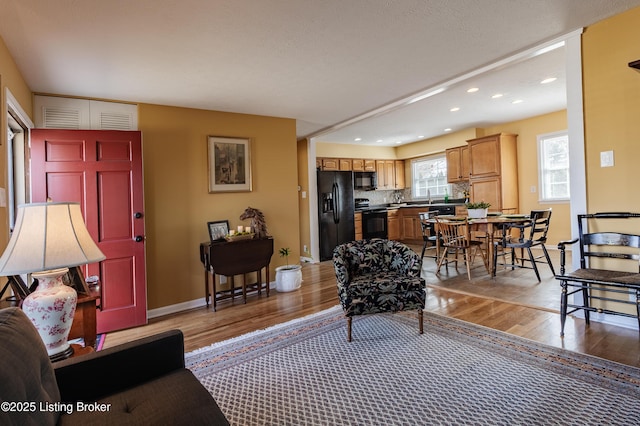 living area with light wood-style flooring, recessed lighting, and baseboards