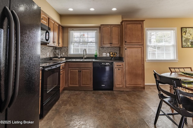 kitchen with dark countertops, a healthy amount of sunlight, black appliances, and a sink