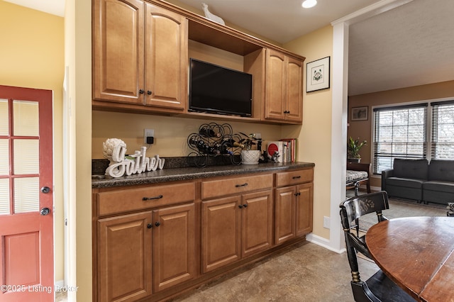 kitchen featuring dark countertops, brown cabinetry, and baseboards