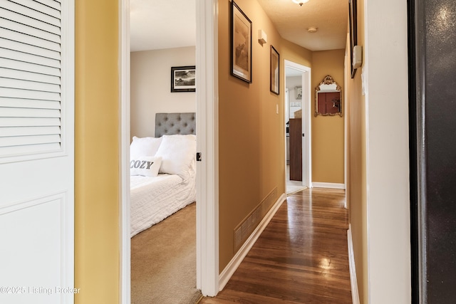 hall with dark colored carpet, baseboards, and dark wood finished floors