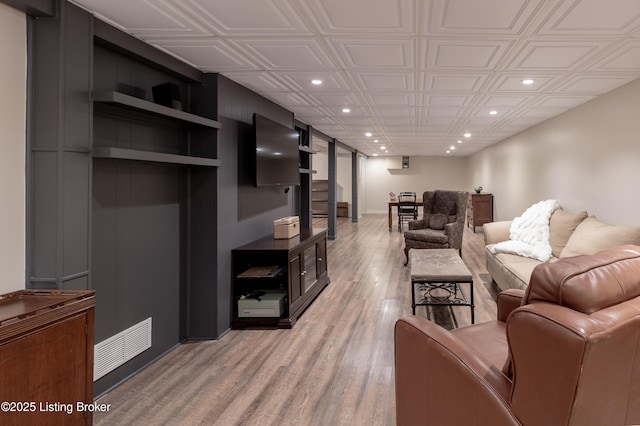 living area featuring light wood-style flooring, recessed lighting, visible vents, and an ornate ceiling