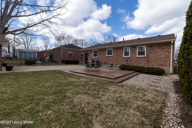 back of property featuring a yard, brick siding, and a patio area