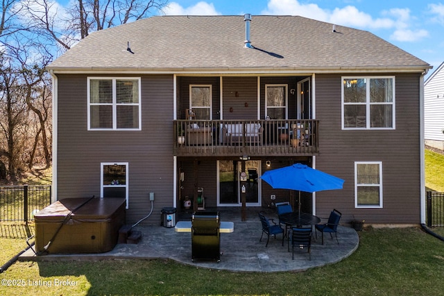 back of property with a shingled roof, a patio, a yard, and a hot tub