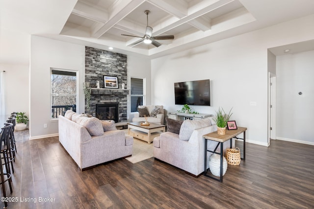 living area with a stone fireplace, beam ceiling, dark wood finished floors, and coffered ceiling