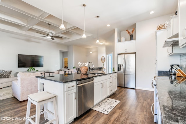 kitchen with a sink, under cabinet range hood, coffered ceiling, open floor plan, and appliances with stainless steel finishes