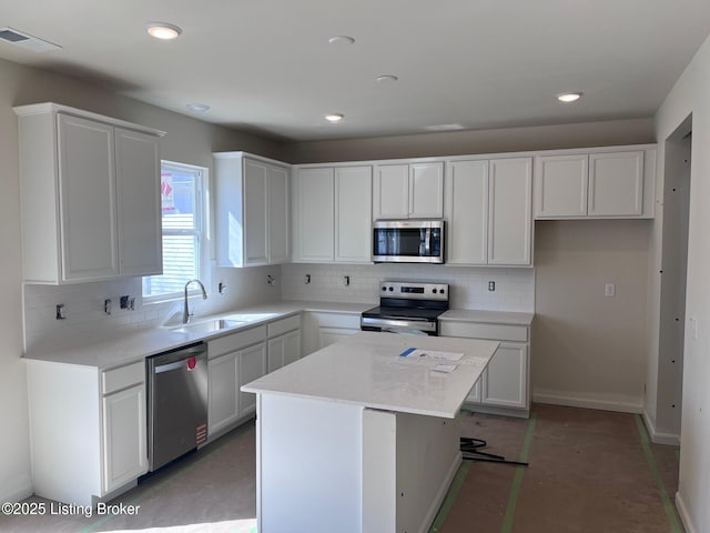 kitchen featuring visible vents, a sink, appliances with stainless steel finishes, backsplash, and a center island