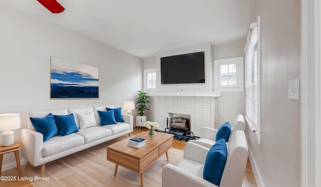 living area featuring baseboards, a fireplace, and light wood finished floors